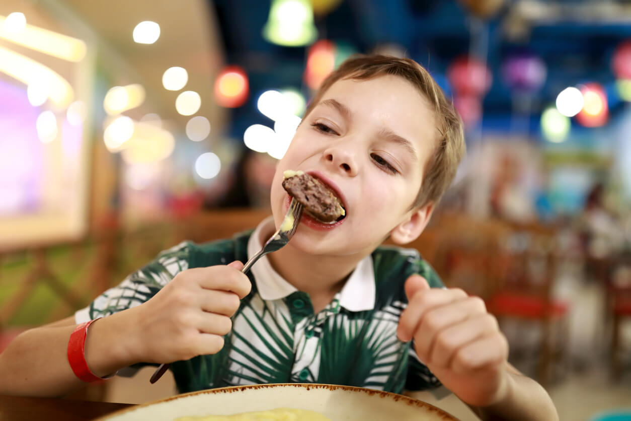 A child eating beef with a fork.