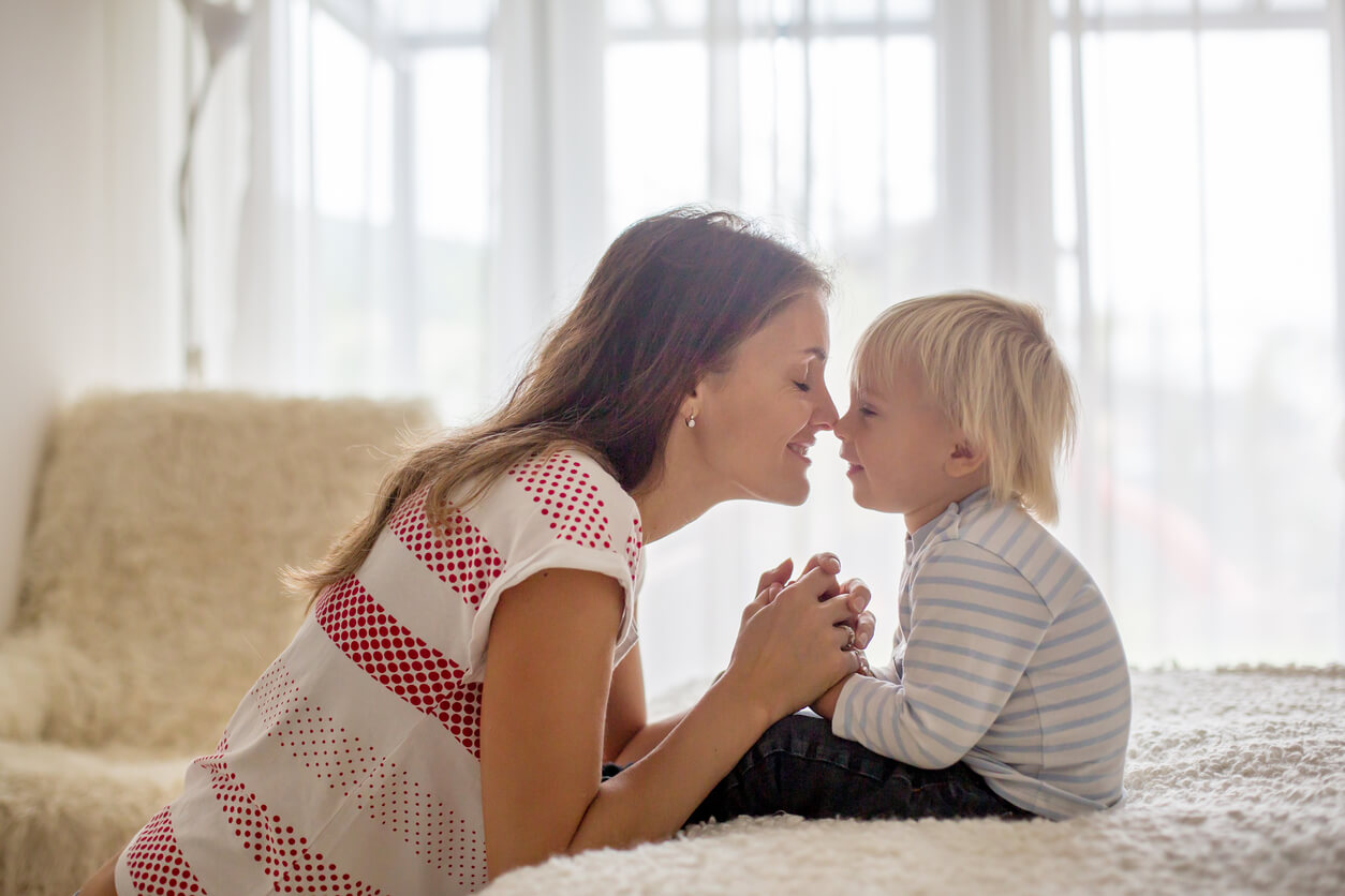 En mor som kneler på bakken for å nusse småbarnsnesen.