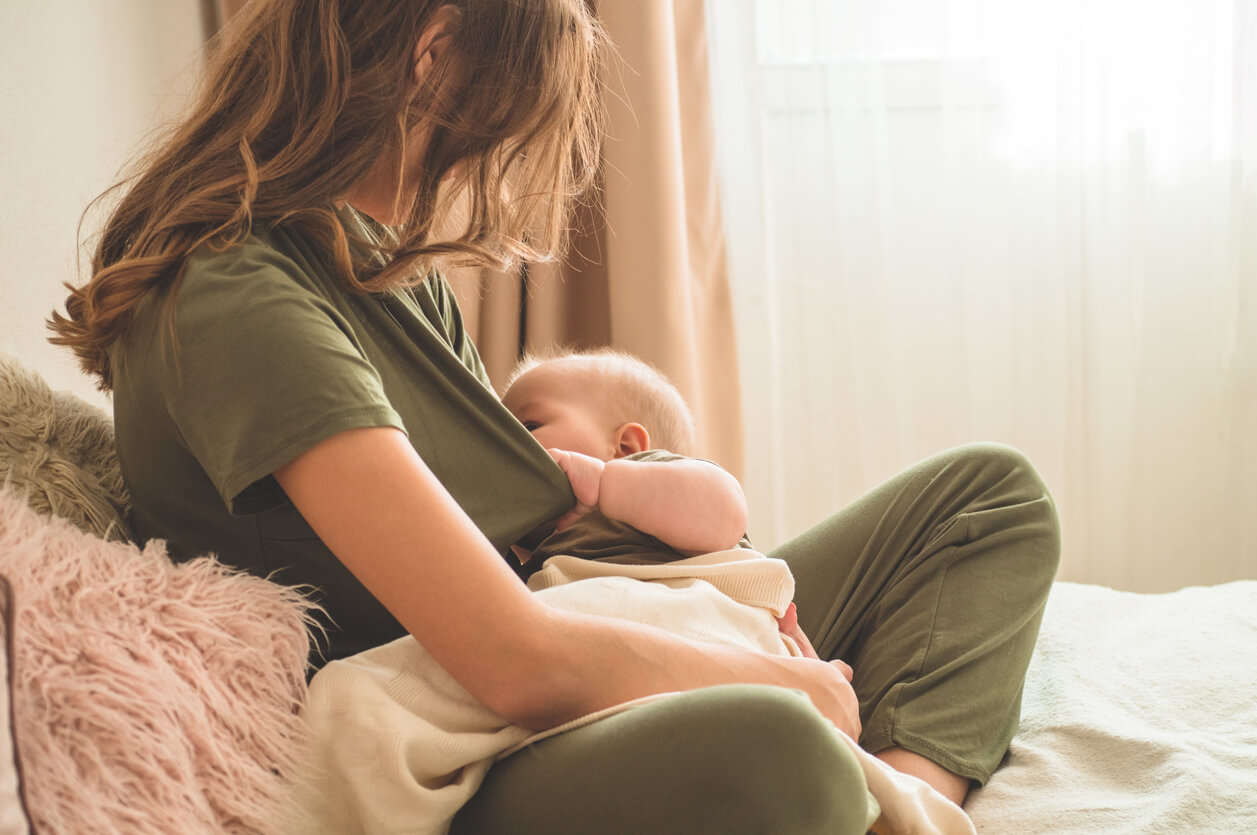 A woman breastfeeding her baby in bed.