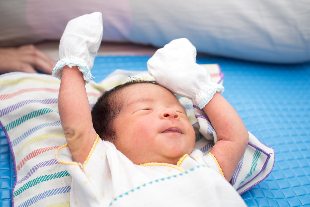 A newborn wearing mittens.