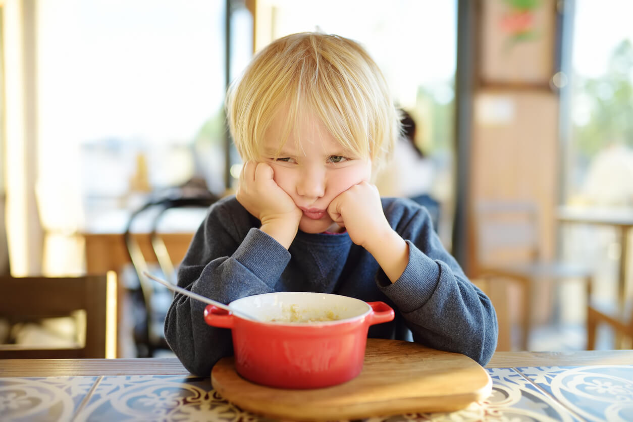 Et barn som ikke vil spise maten foran seg ved bordet.