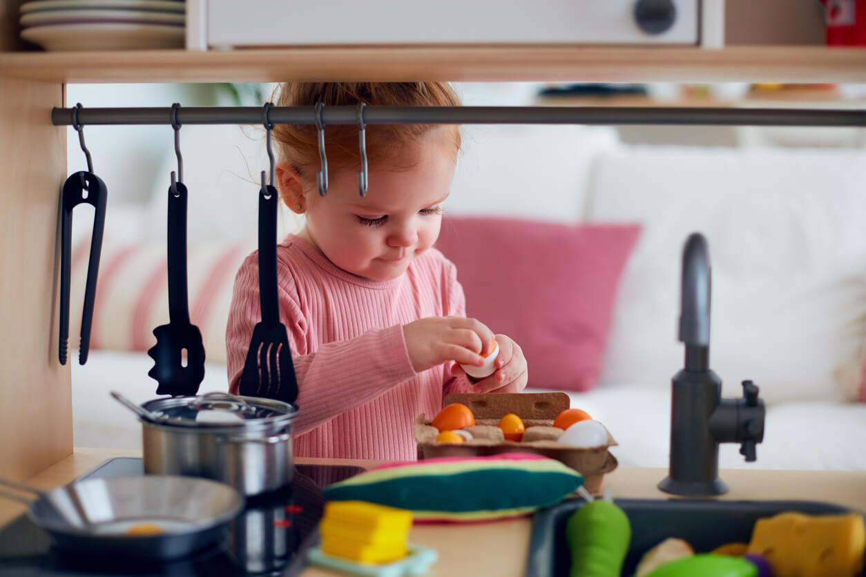 A toddler playing with a toy kitchen.