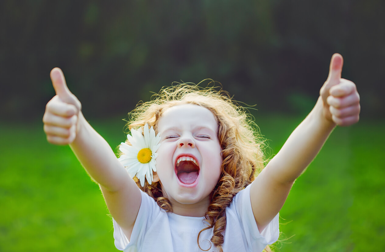 Une jeune fille avec une fleur dans les cheveux qui exprime de la joie.