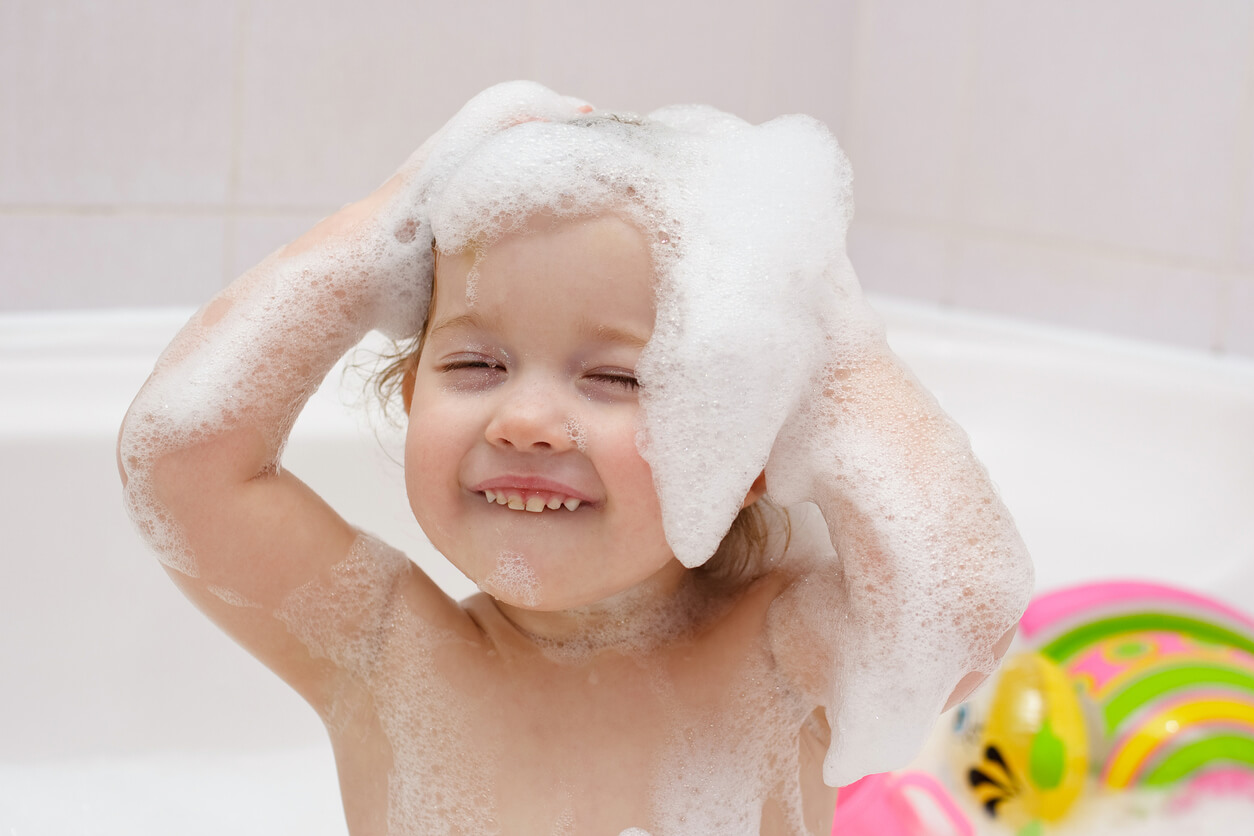 Une jeune fille dans un bain avec de la mousse.