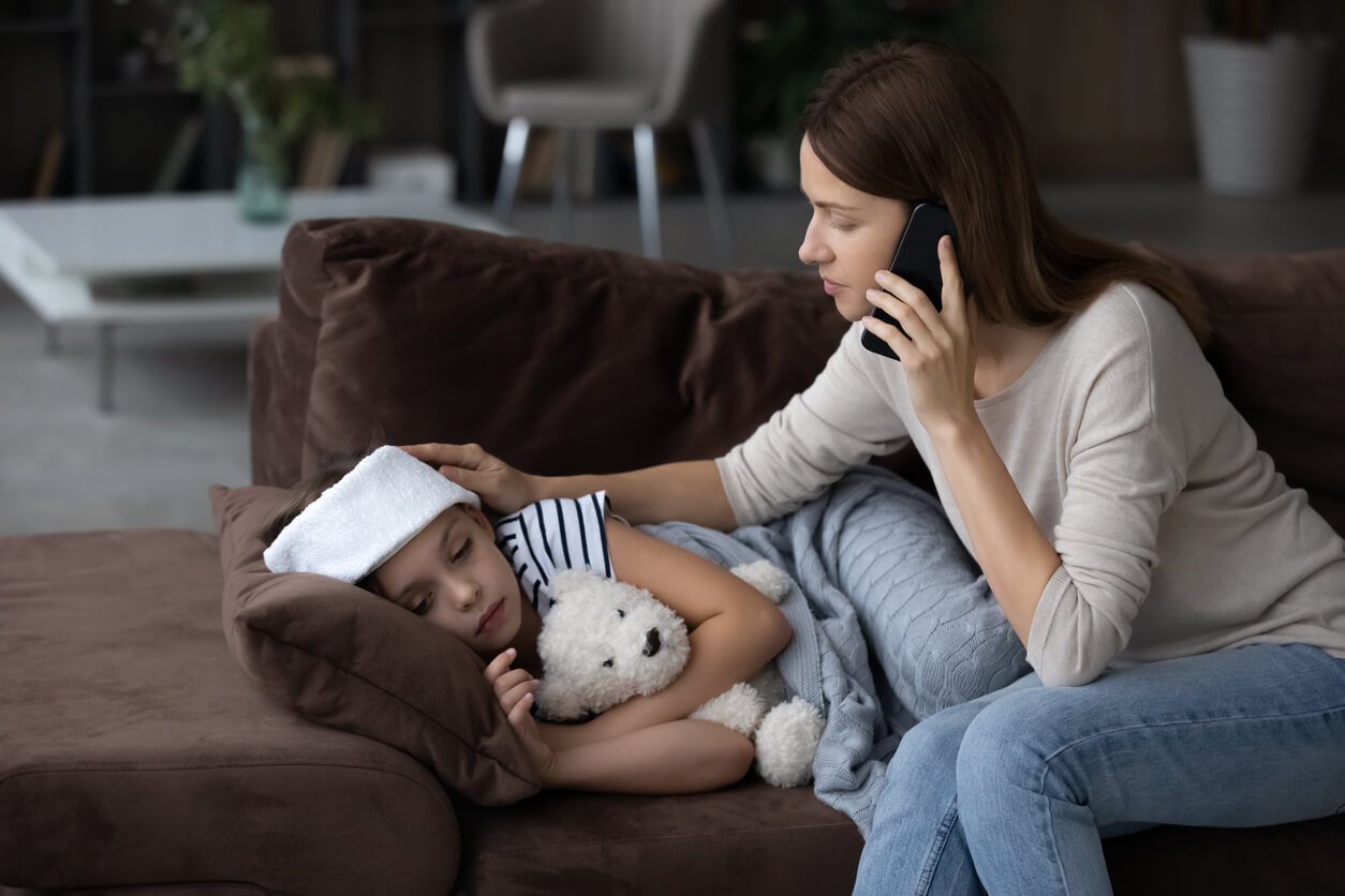 Un enfant malade sur un canapé avec sa maman au téléphone.