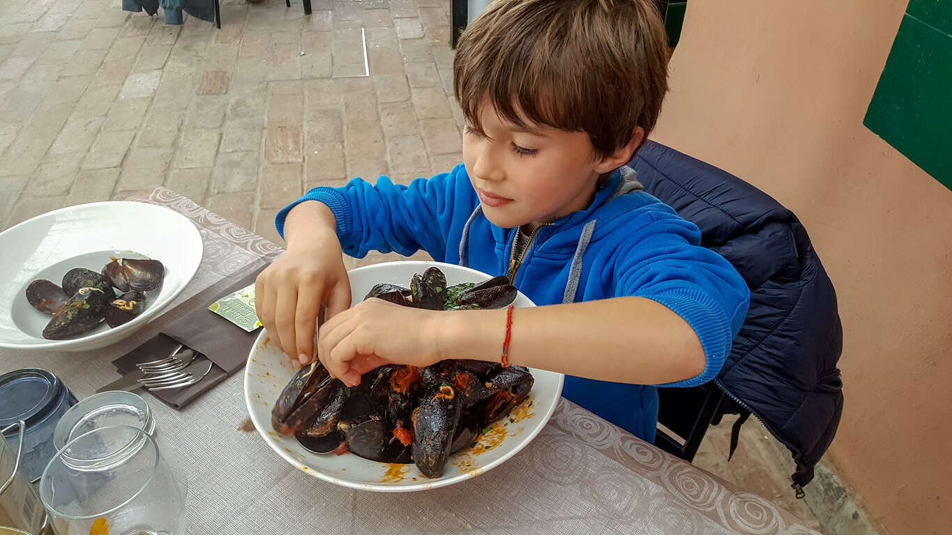 En pojke som förnöjt förtär musslor.