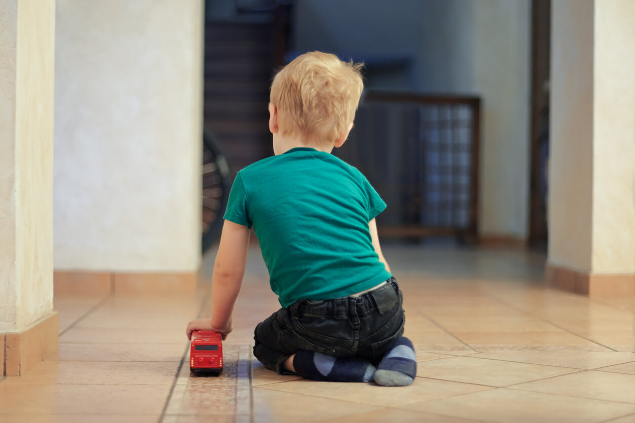 A toddler sitting on the floor playing with a toy truck.