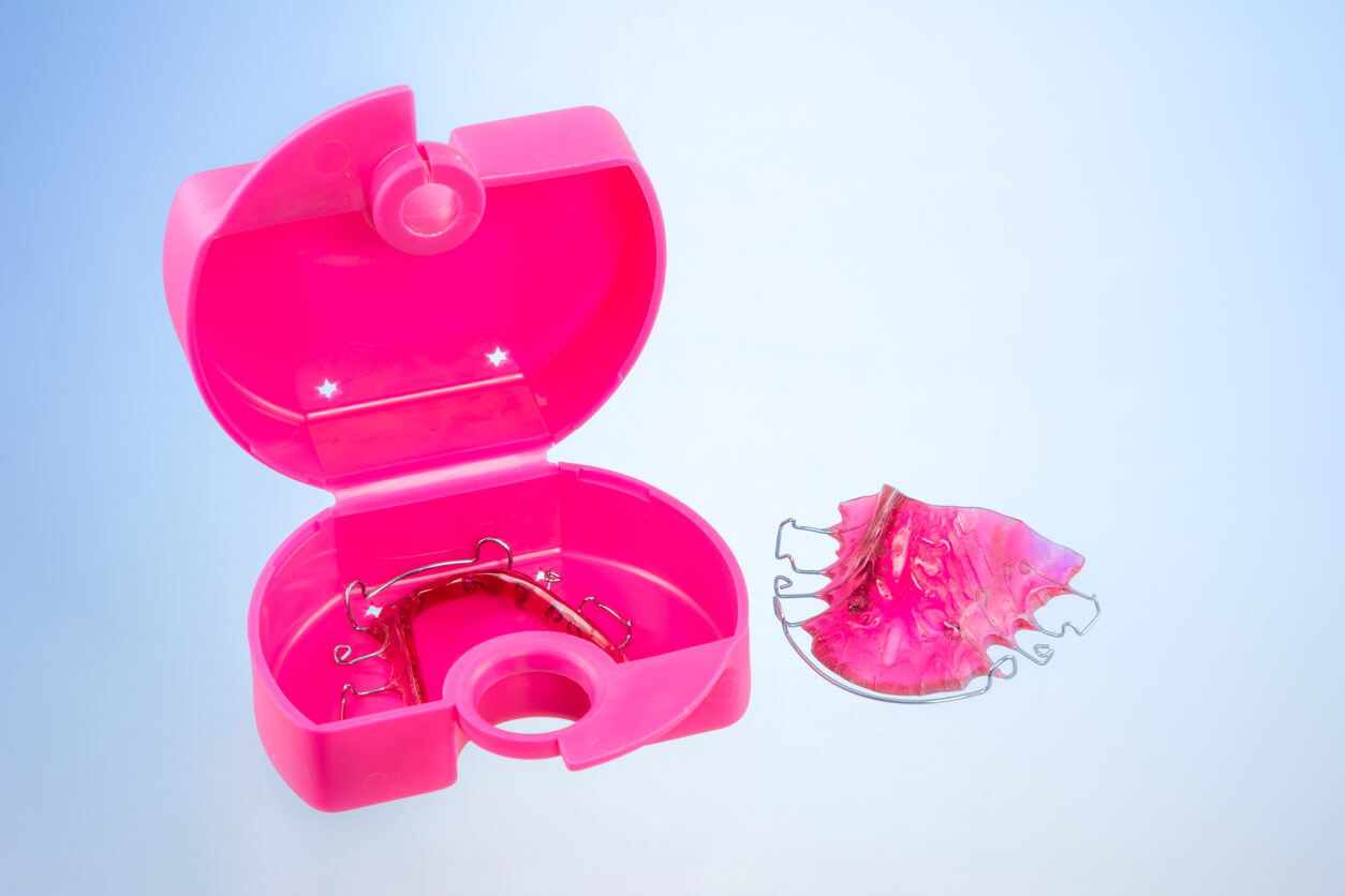 A removable orthodontic appliance in a plastic case.