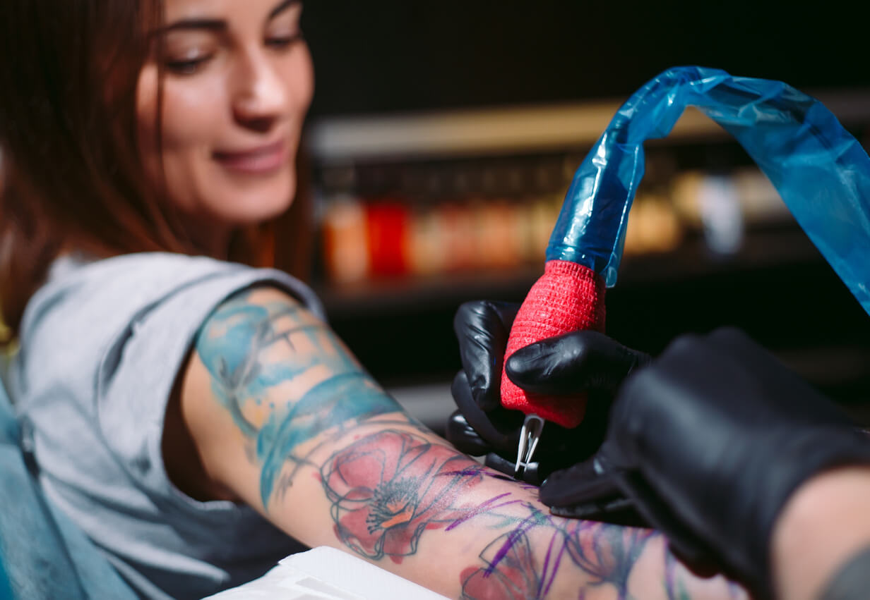 En kvinna som tatuerar sig på armen.