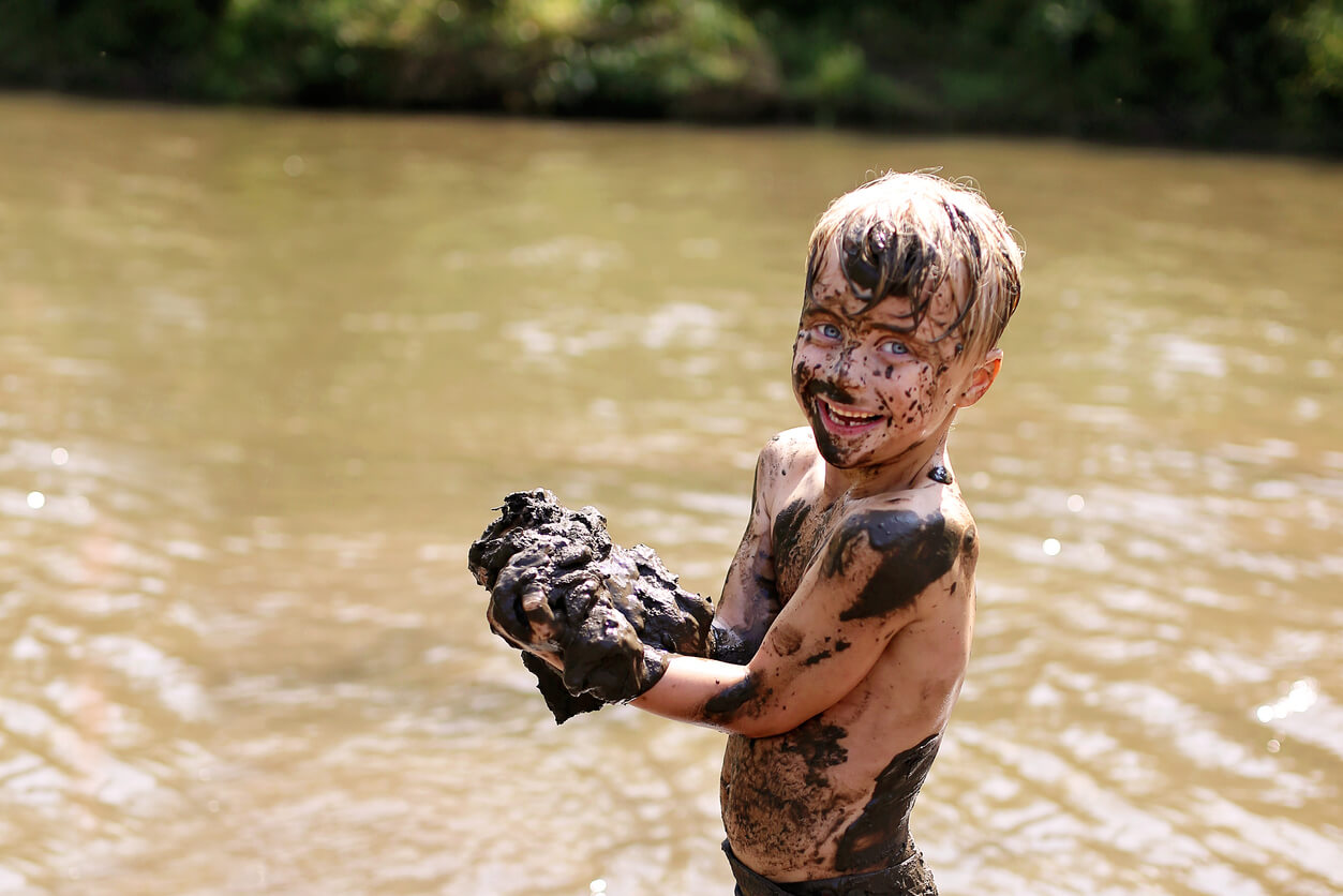 Et barn som leker i en gjørmete elv.