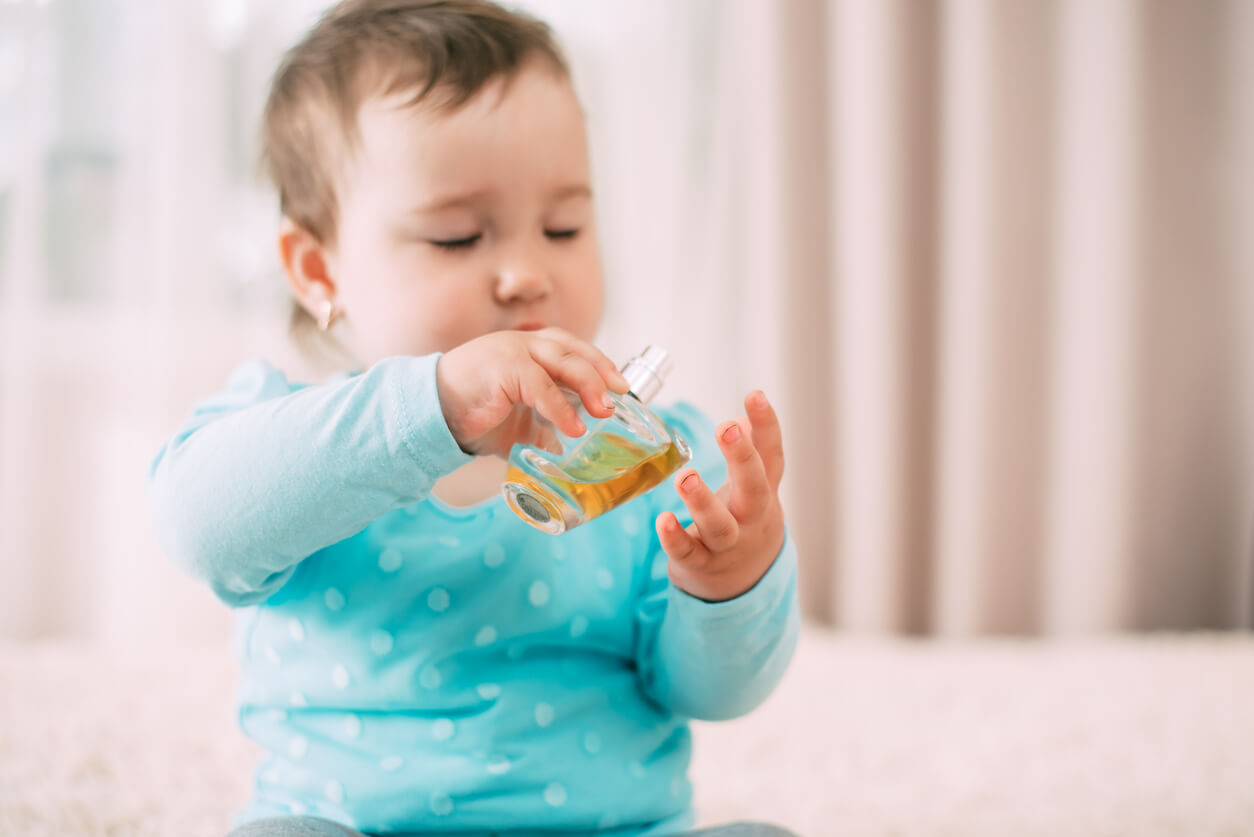 A baby playing with a bottle of perfume.