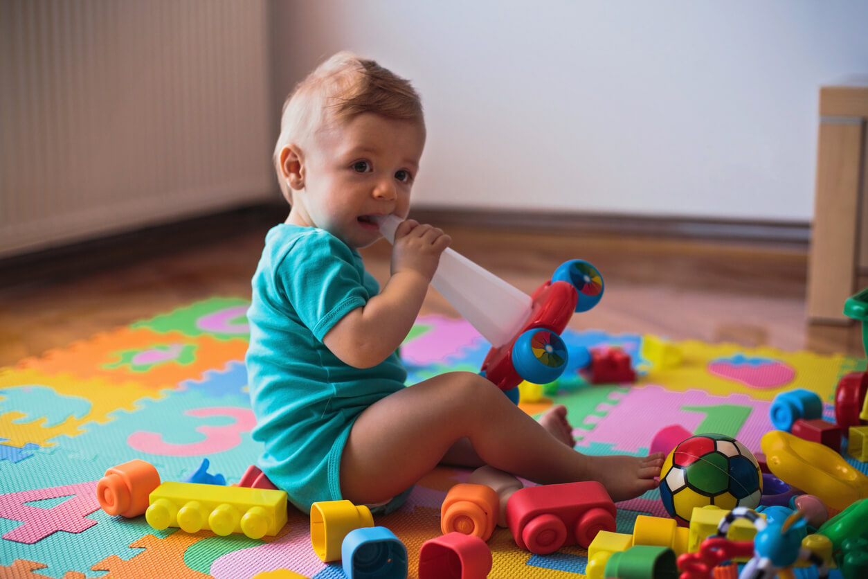 En bebis omgiven av färgglada leksaker.