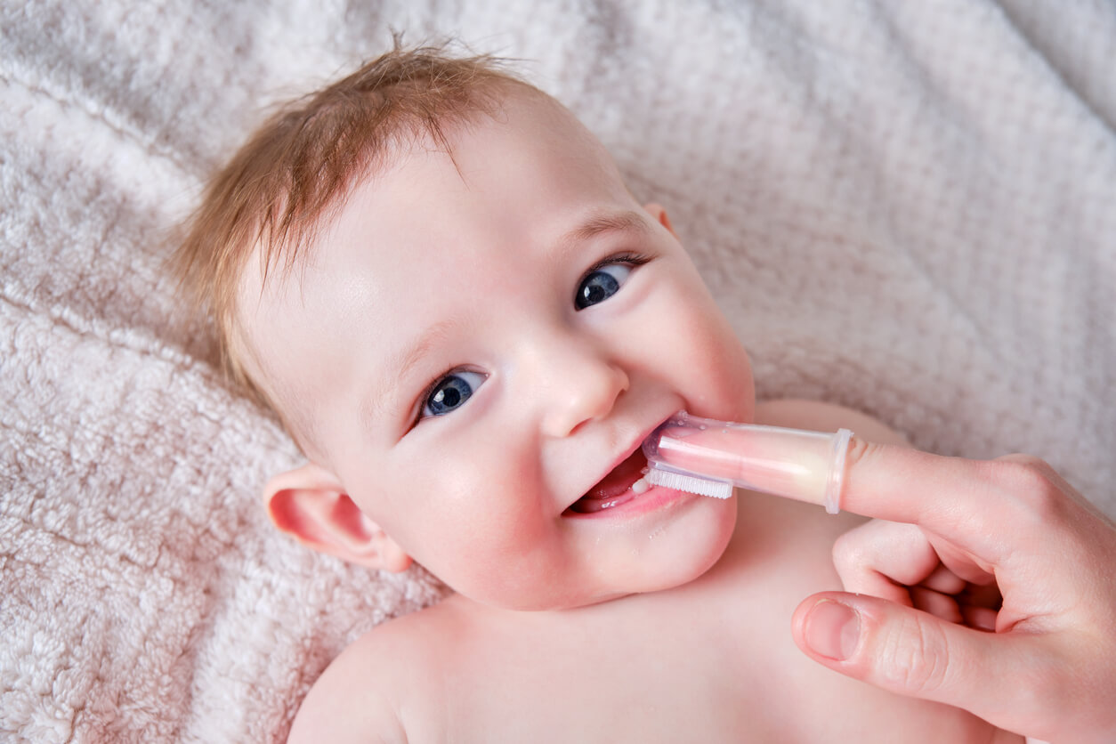 A person brushing a baby's first teeth with a silicone finger brush.