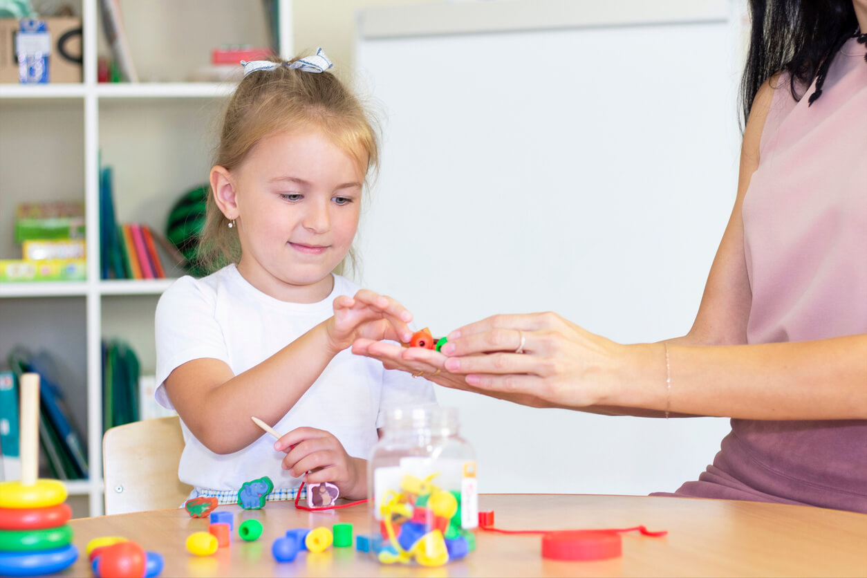 Une jeune fille qui fait une activité avec des perles;