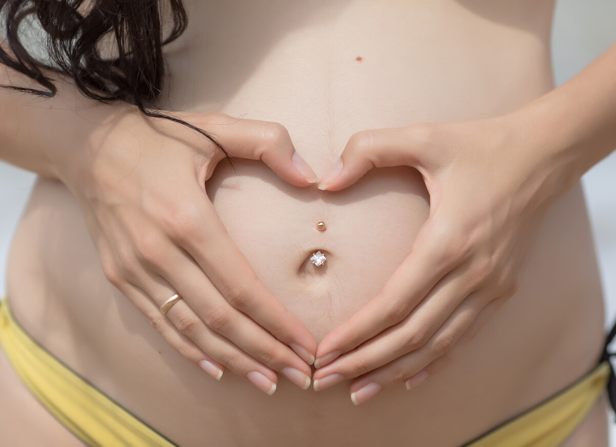 A pregnant woman with a naval piercing.