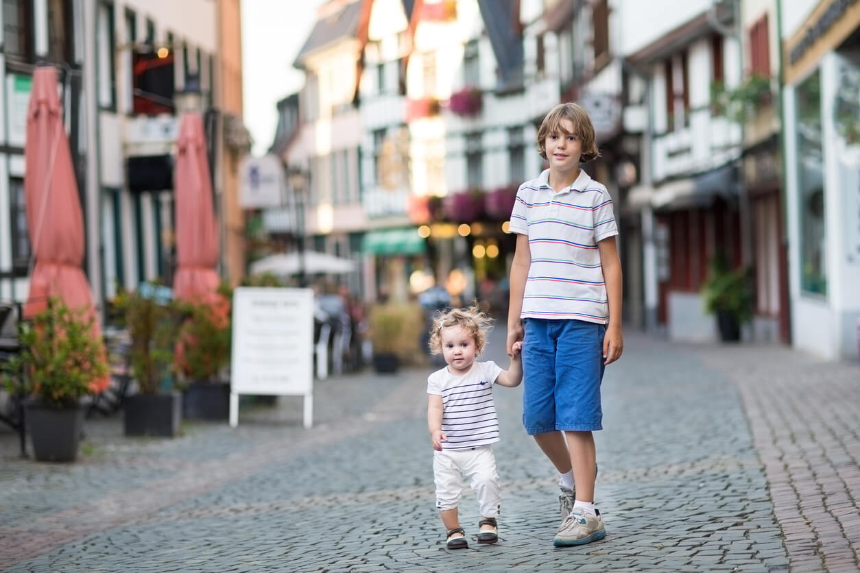 En äldre bror går nerför gatan med sin lillasyster.