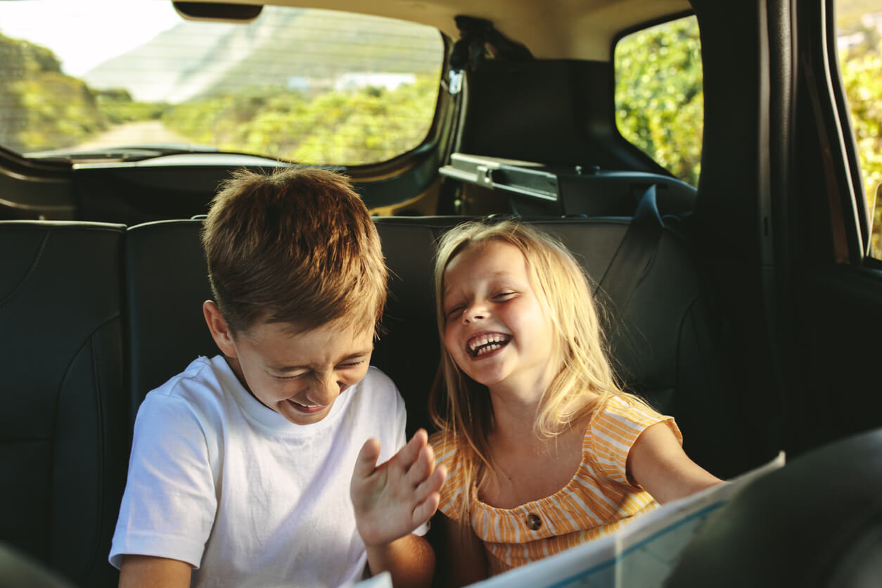 Children laughing in the back seat of a car.