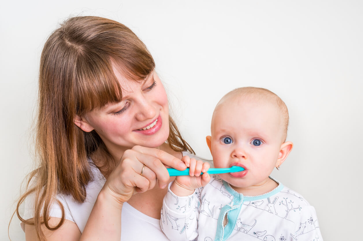 En mamma som borstar tänderna på sin bebis.