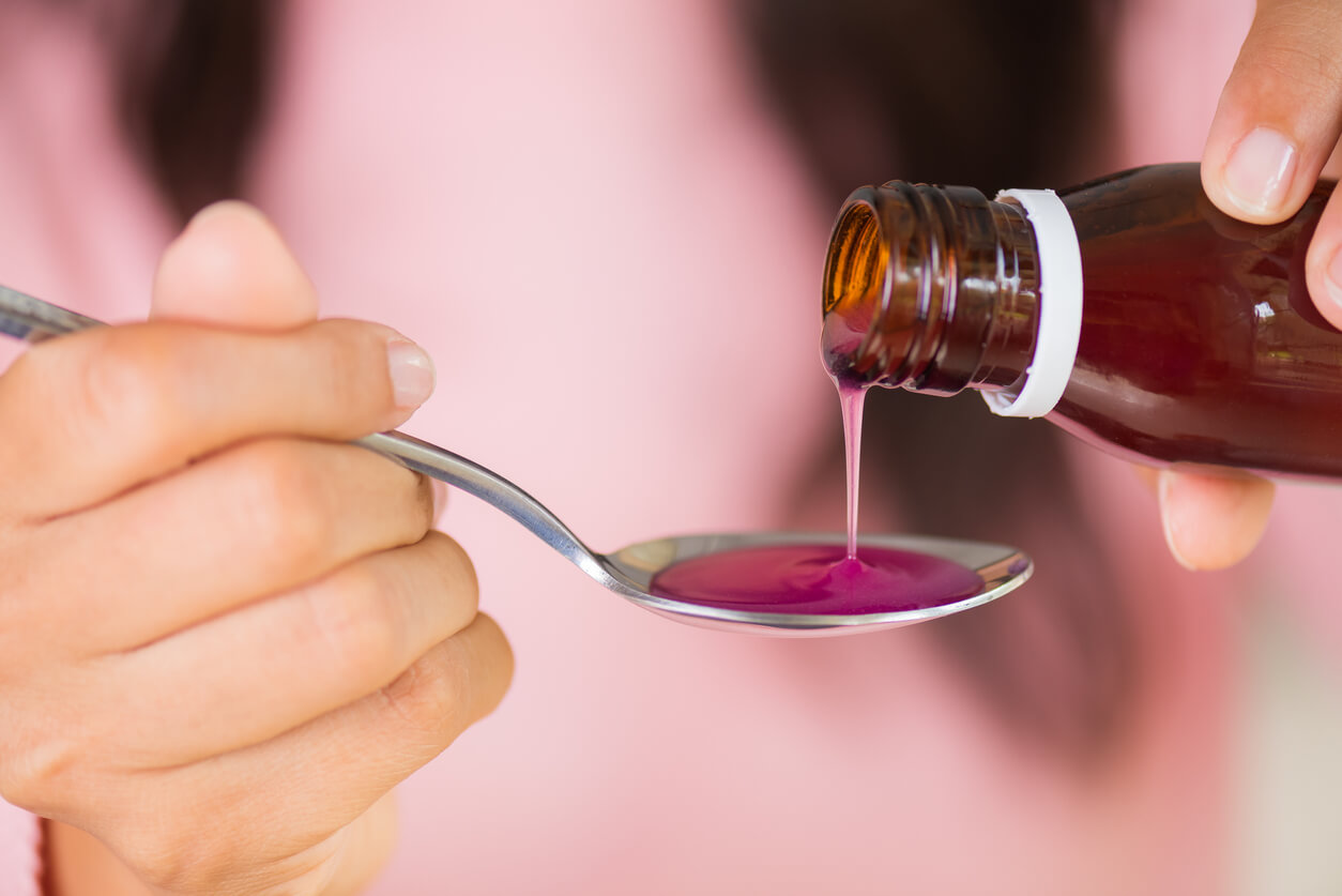 A woman pouring syrup into a spoon.