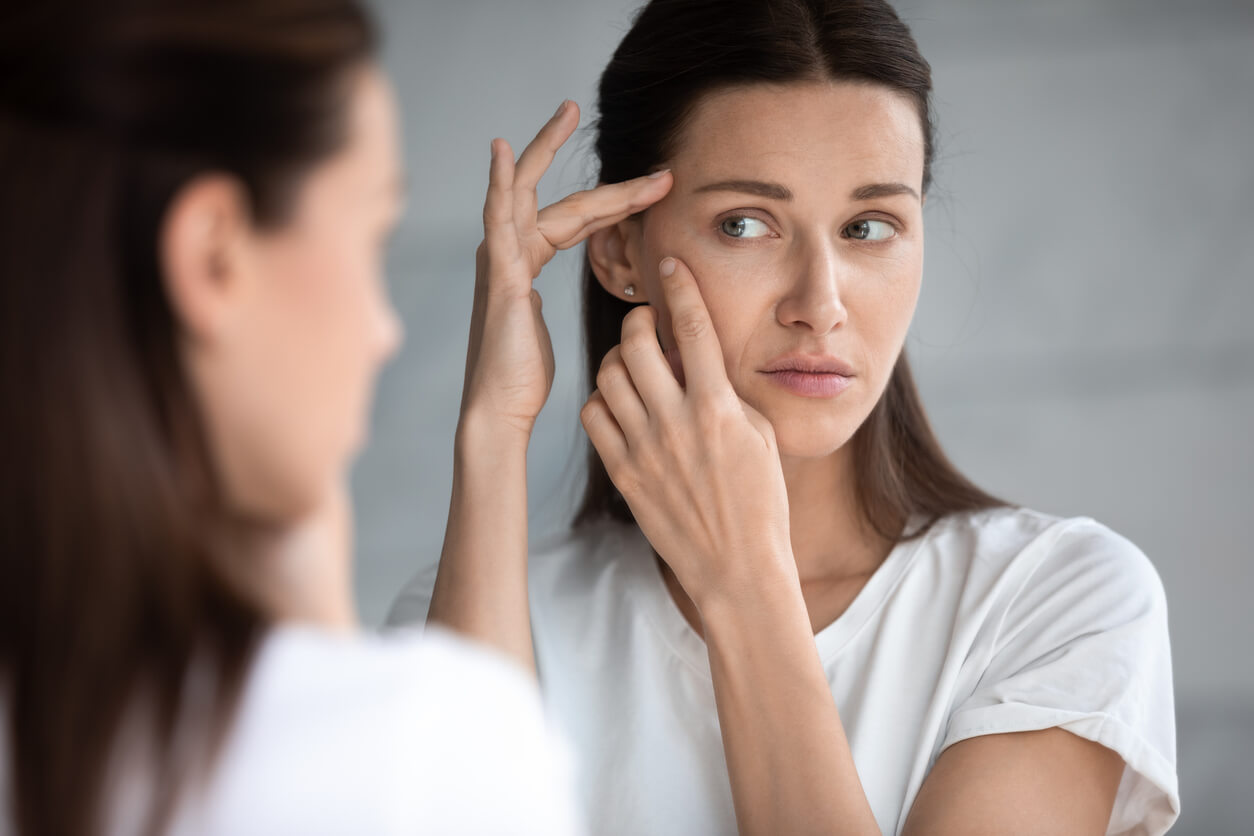 A woman checking her face for acne.
