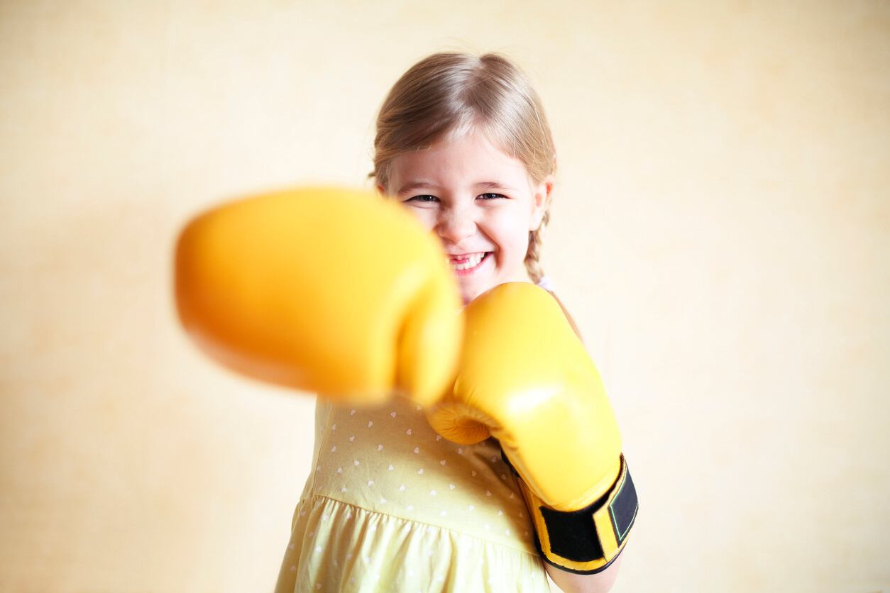 A young girl wearing boxing gloves.