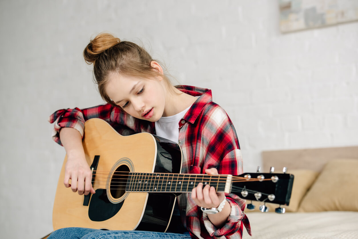 A teenage girl playing the guitar.