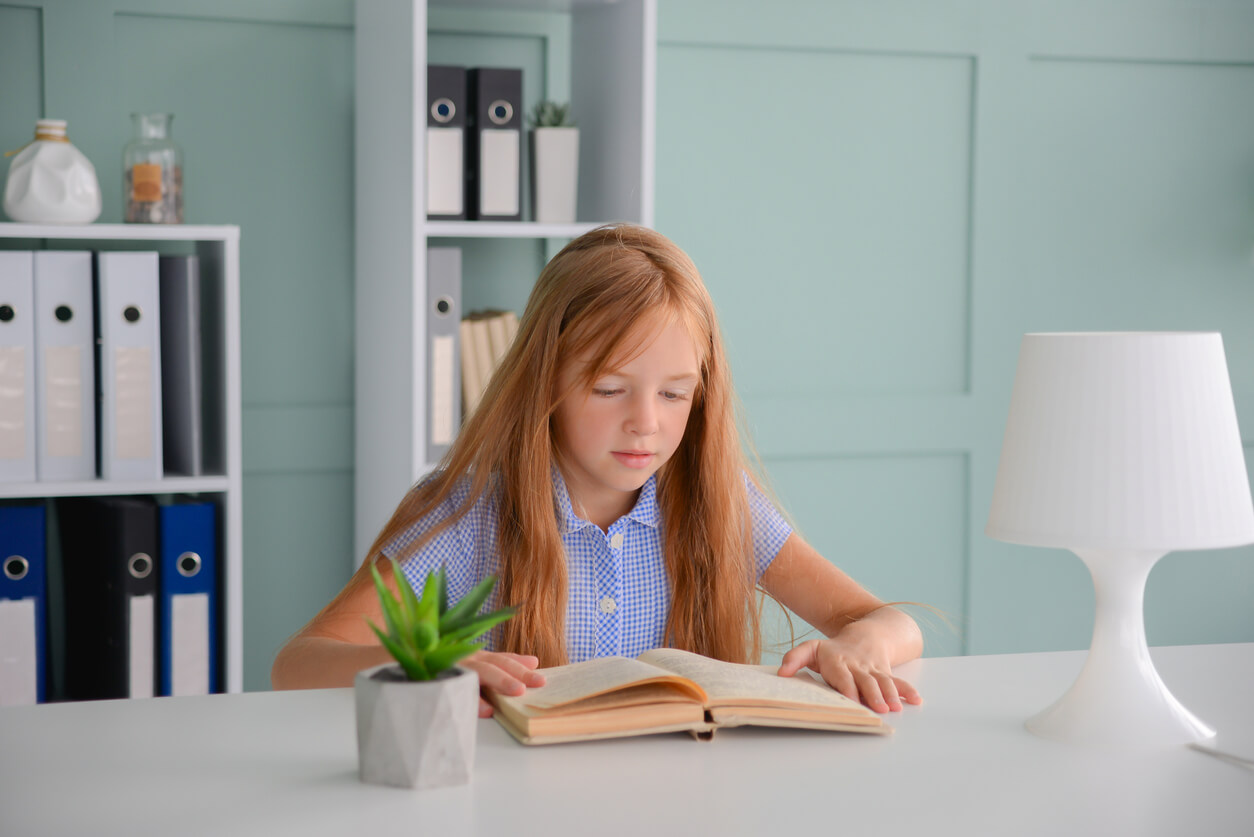 Une jeune fille qui lit à son bureau.
