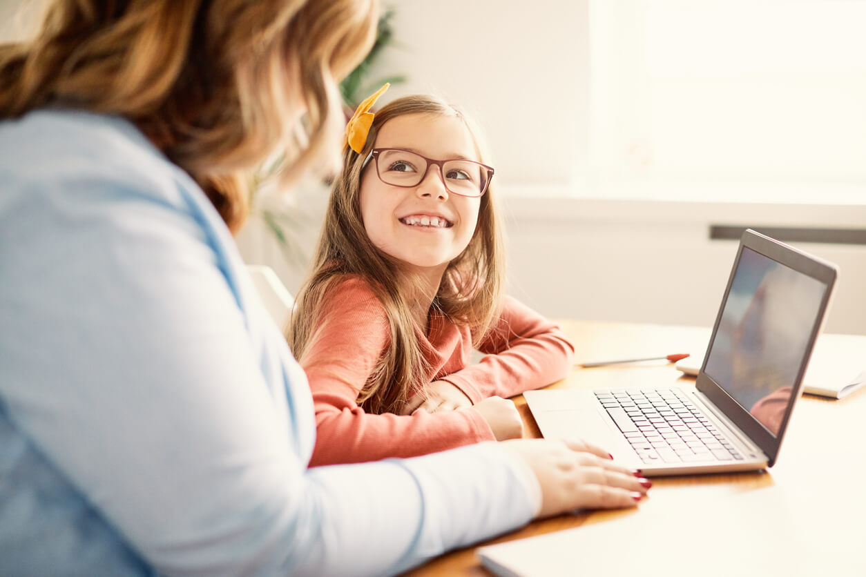 Une jeune fille avec une adulte devant un ordinateur. 