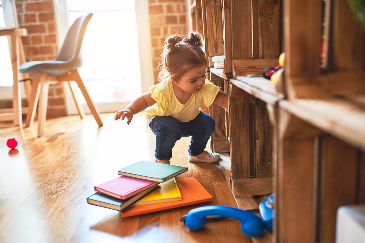A preschooler taking books off a shelf.
