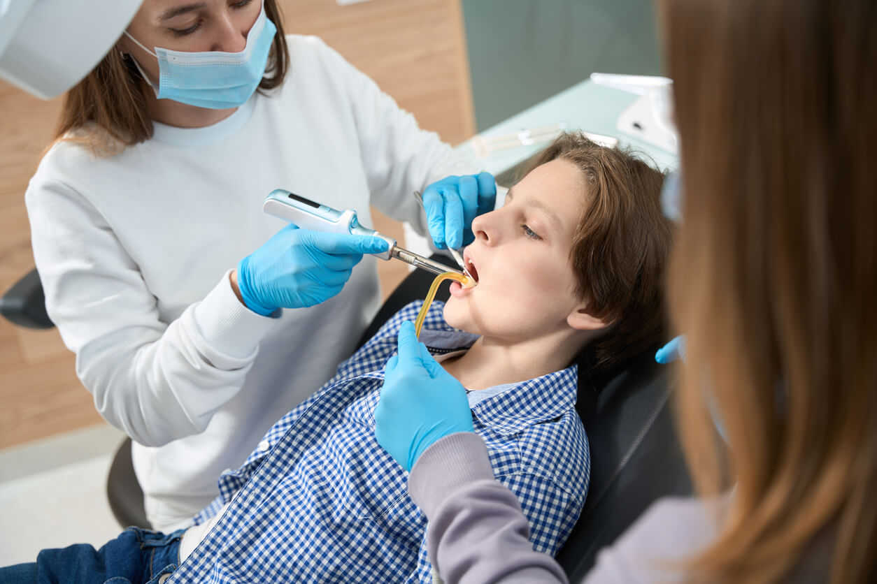 An orthodontist working on a teen's mouth.