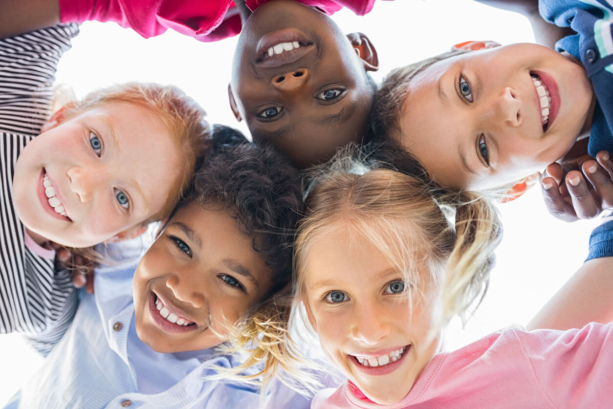 A diverse group of students with their arms around one another.