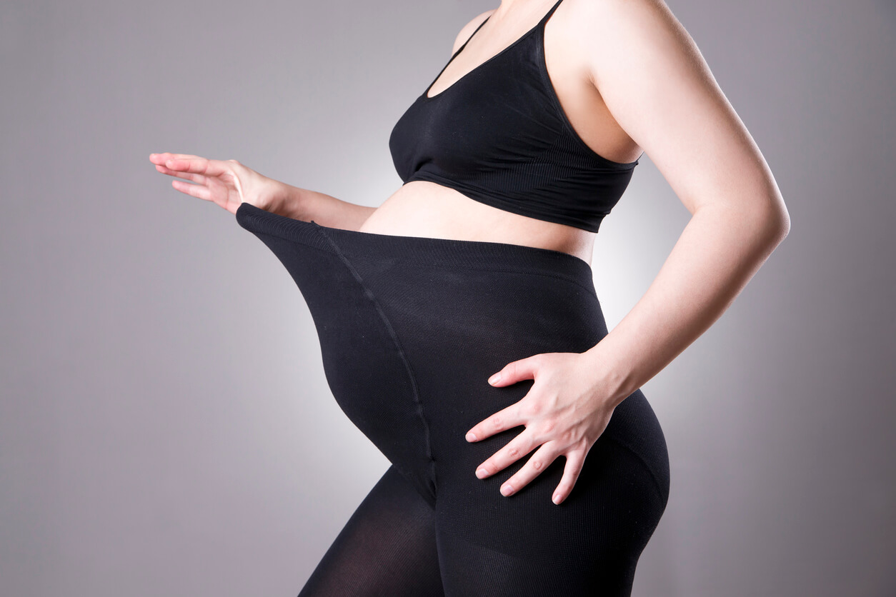 En gravid kvinne iført svarte strømpebukser.