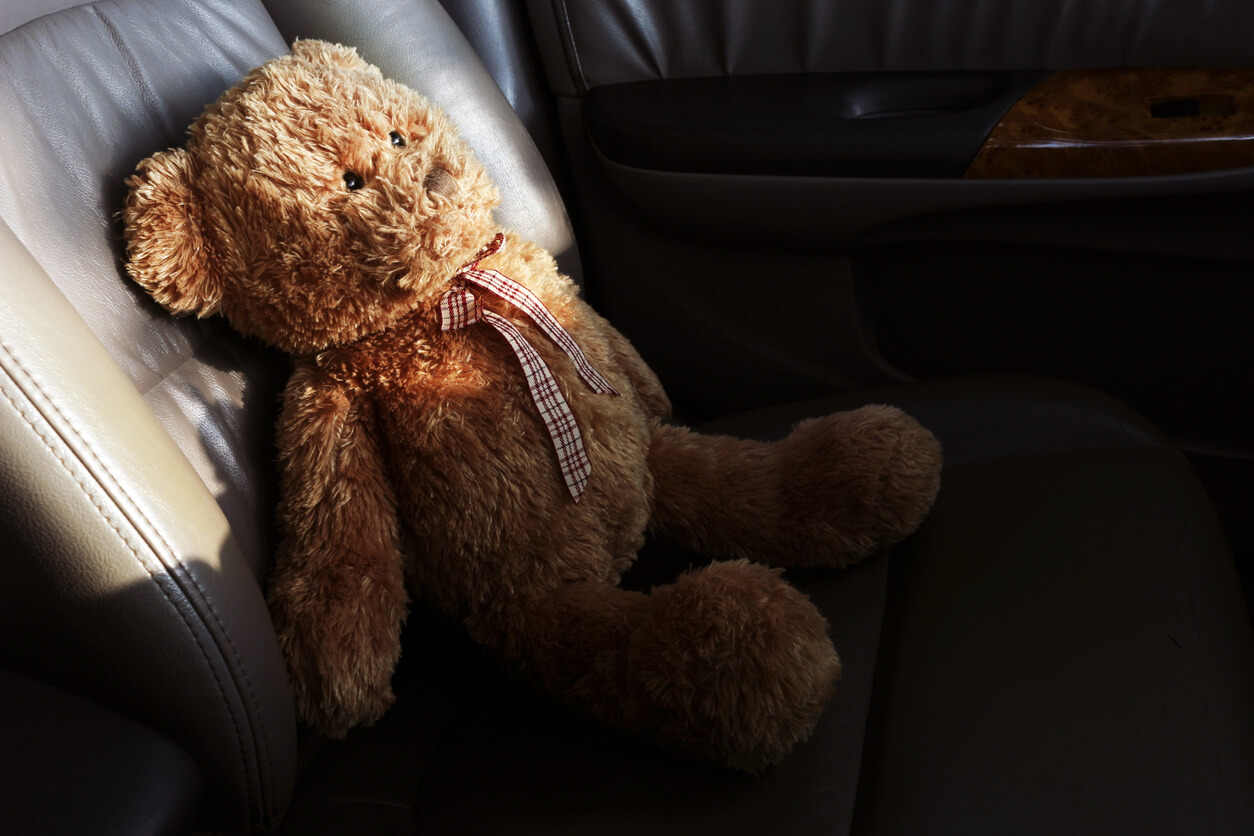 A teddy bear sitting in the seat of a car.