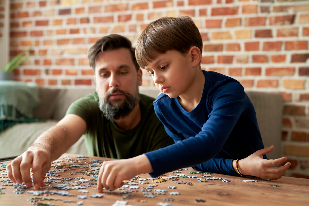 Un père et son fils qui font un puzzle. 