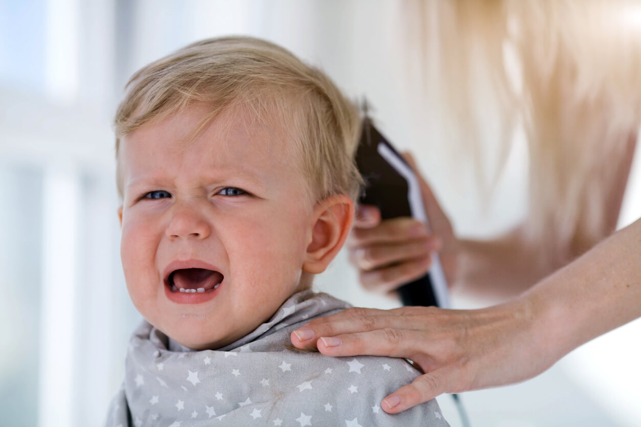A toddler boy crying during a haircut.