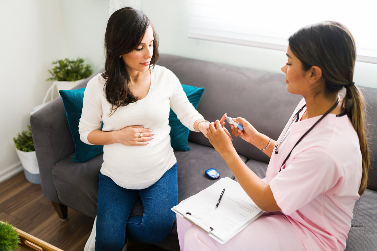 A doctor checking a pregnant woman's blood sugar.