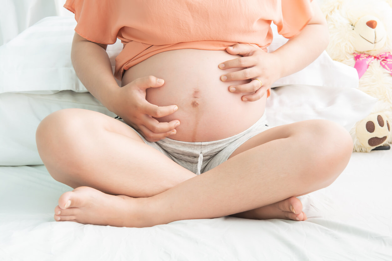 Une femme enceinte qui se gratte le ventre. 