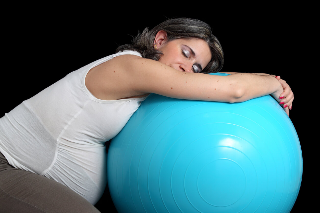 Une femme enceinte qui s'étire avec une fitball.