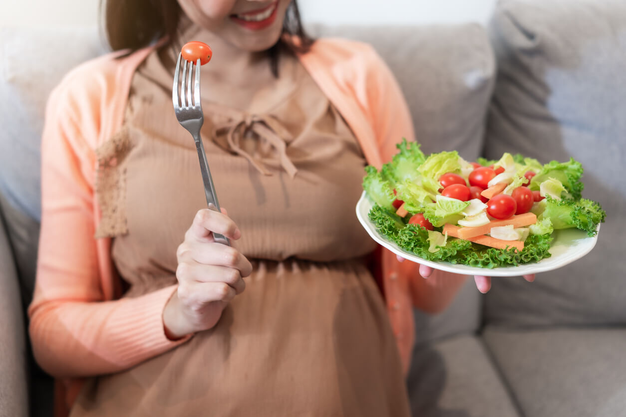 A pregnant woman eating a salad.