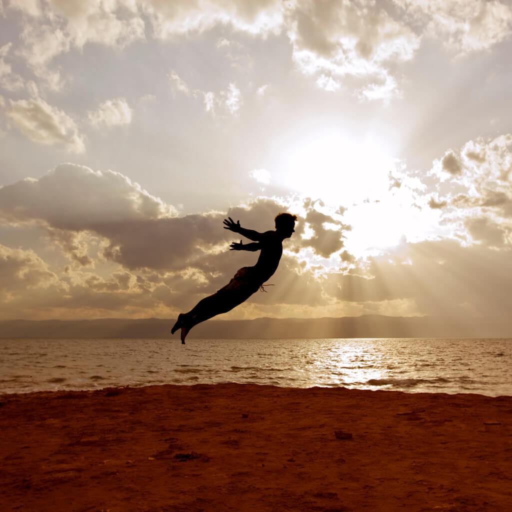 A man jumping in the air at the beach.