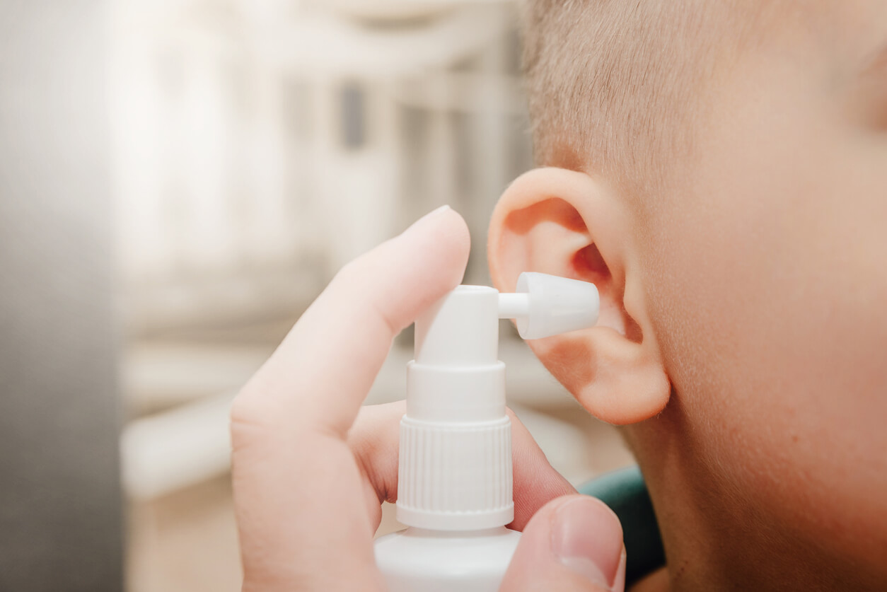 En person som applicerar en spray på ett barns öra.