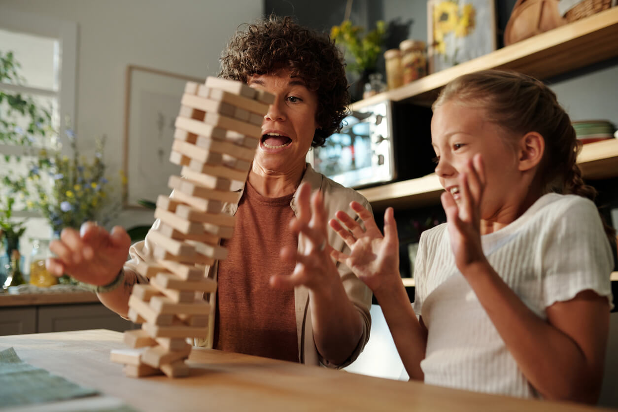 A mother and daughter playing jenga just as the tower falls over.
