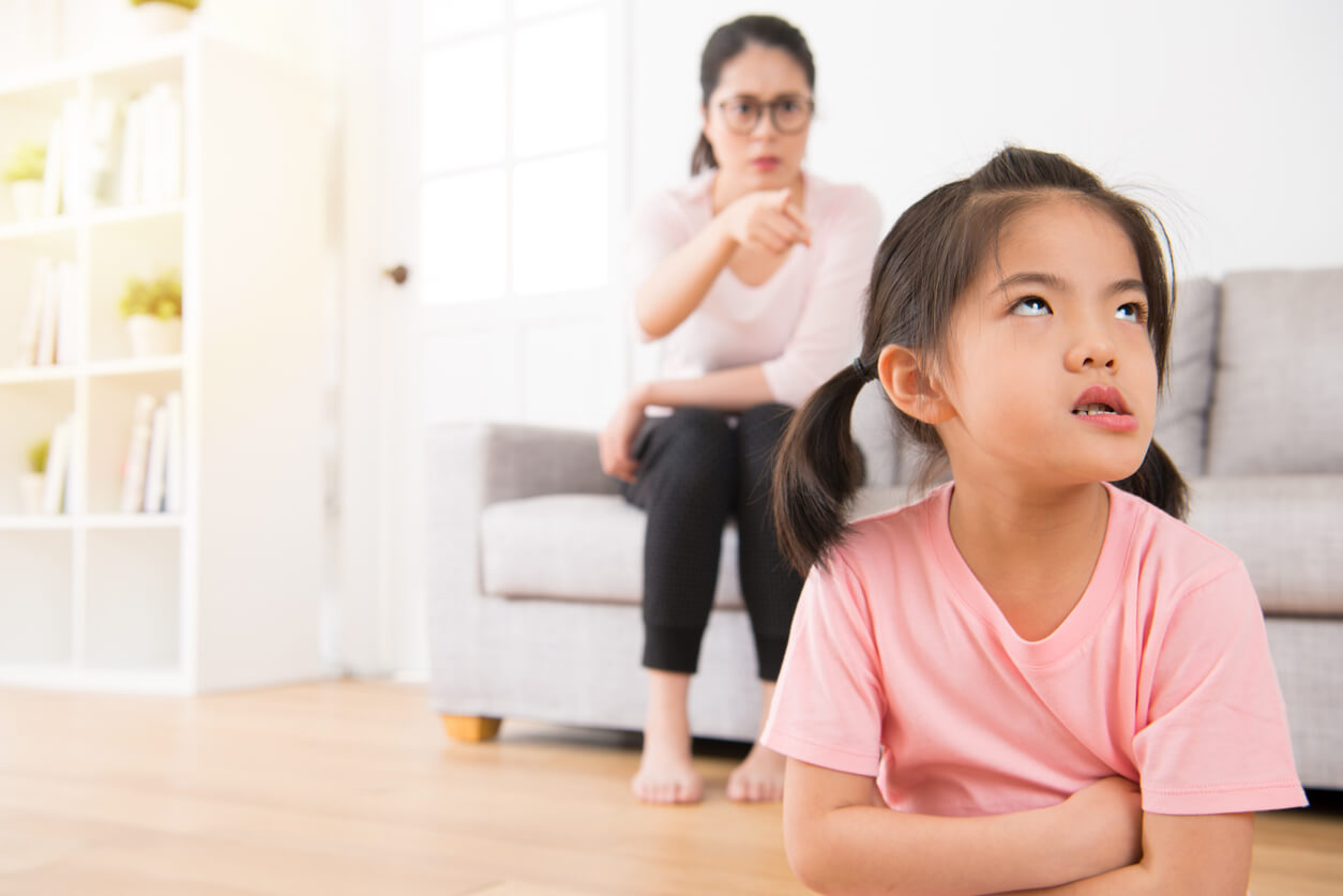A little Asian girl who's rolling her eyes while her mother scolds her.