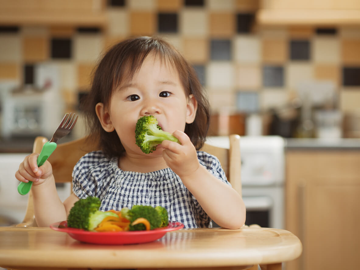 Un enfant qui mange du brocoli. 