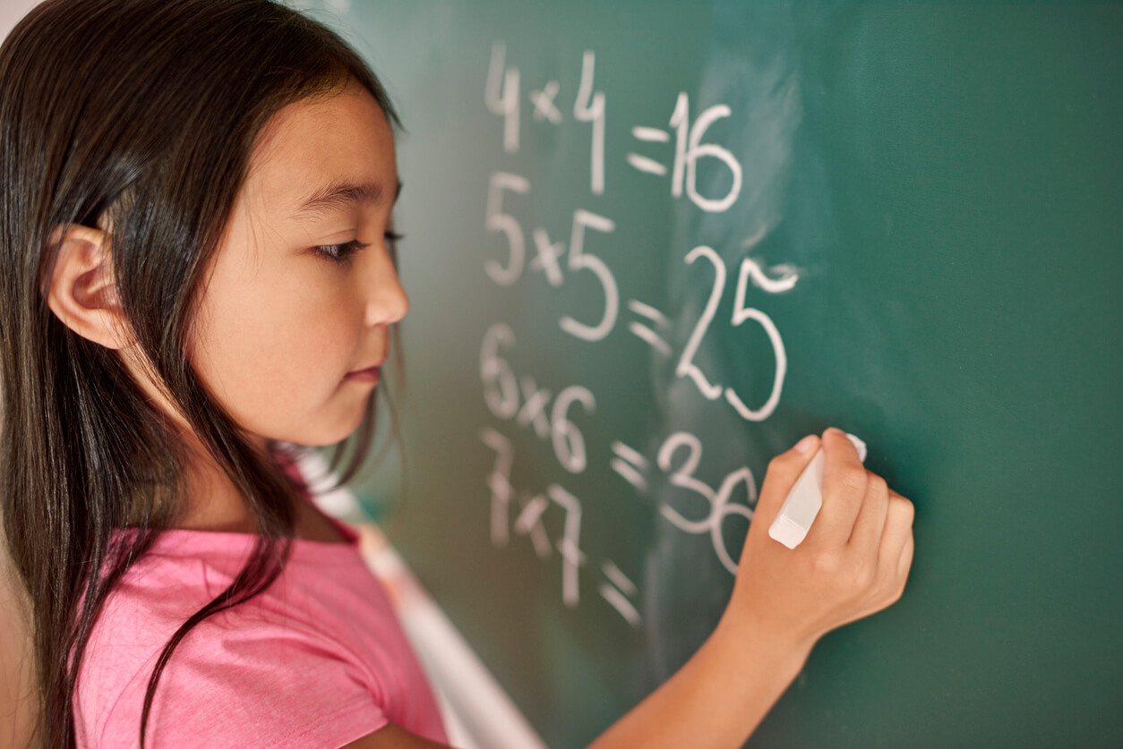 A young girl doing math on the chalkboard.