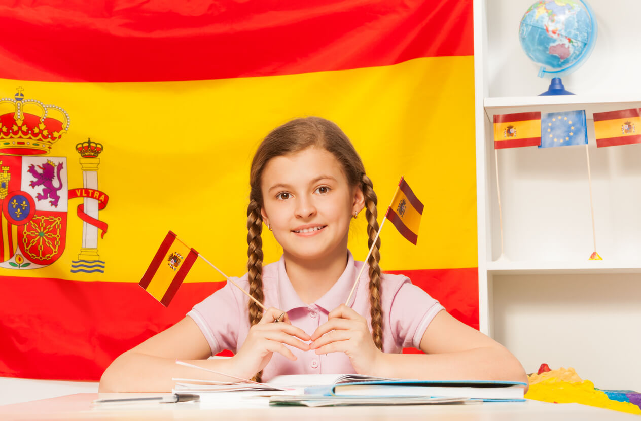 Une jeune fille assise devant le drapeau espagnol. 