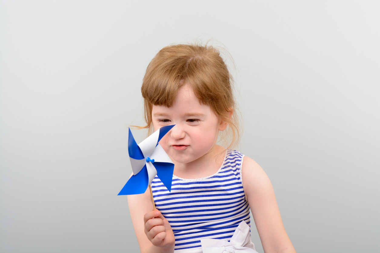 Une jeune fille qui joue avec un moulinet en papier.