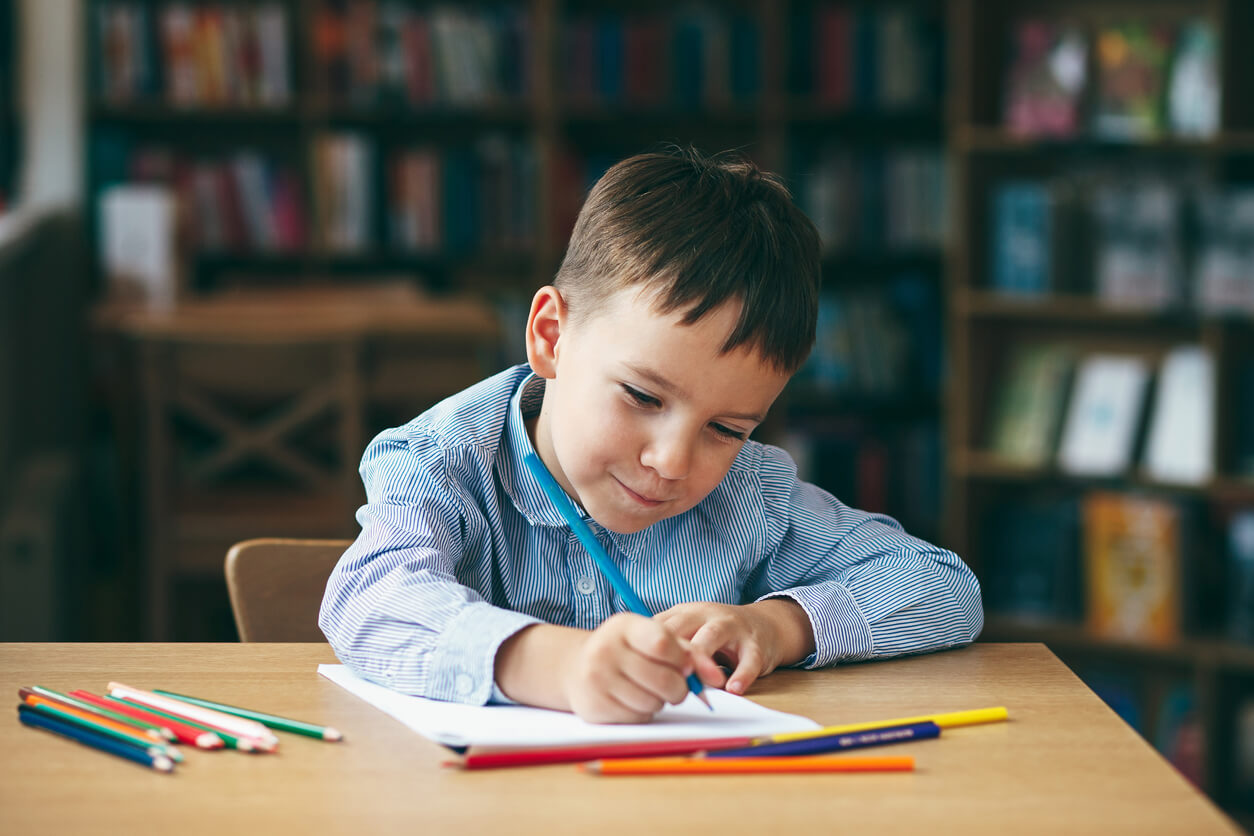 A young child coloring on a notepad.