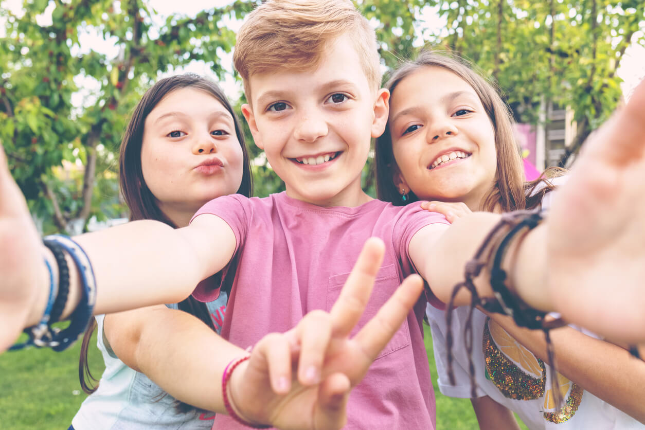 Kolme ekstroverttiä lasta ottamassa selfietä.