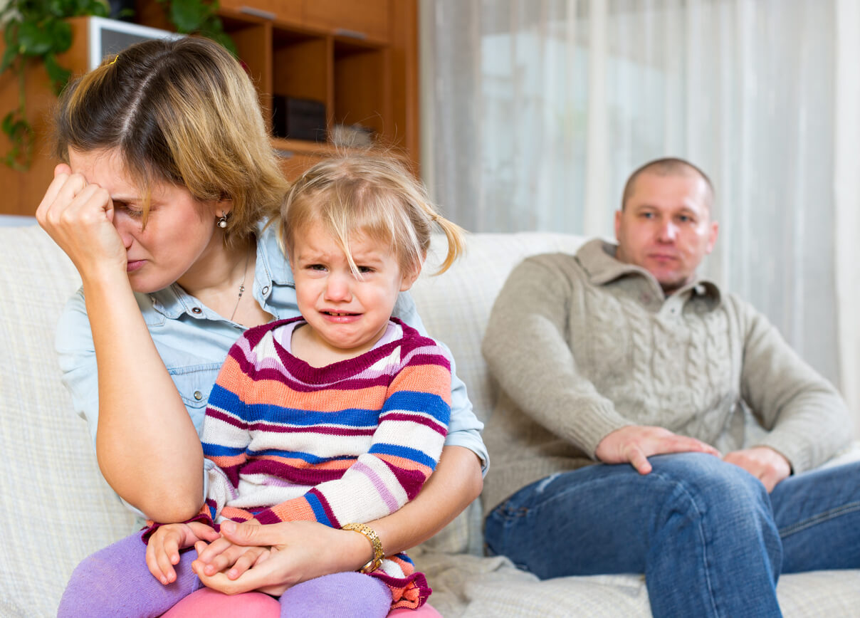 En liten jente som gråter under en konflikt mellom foreldrene.